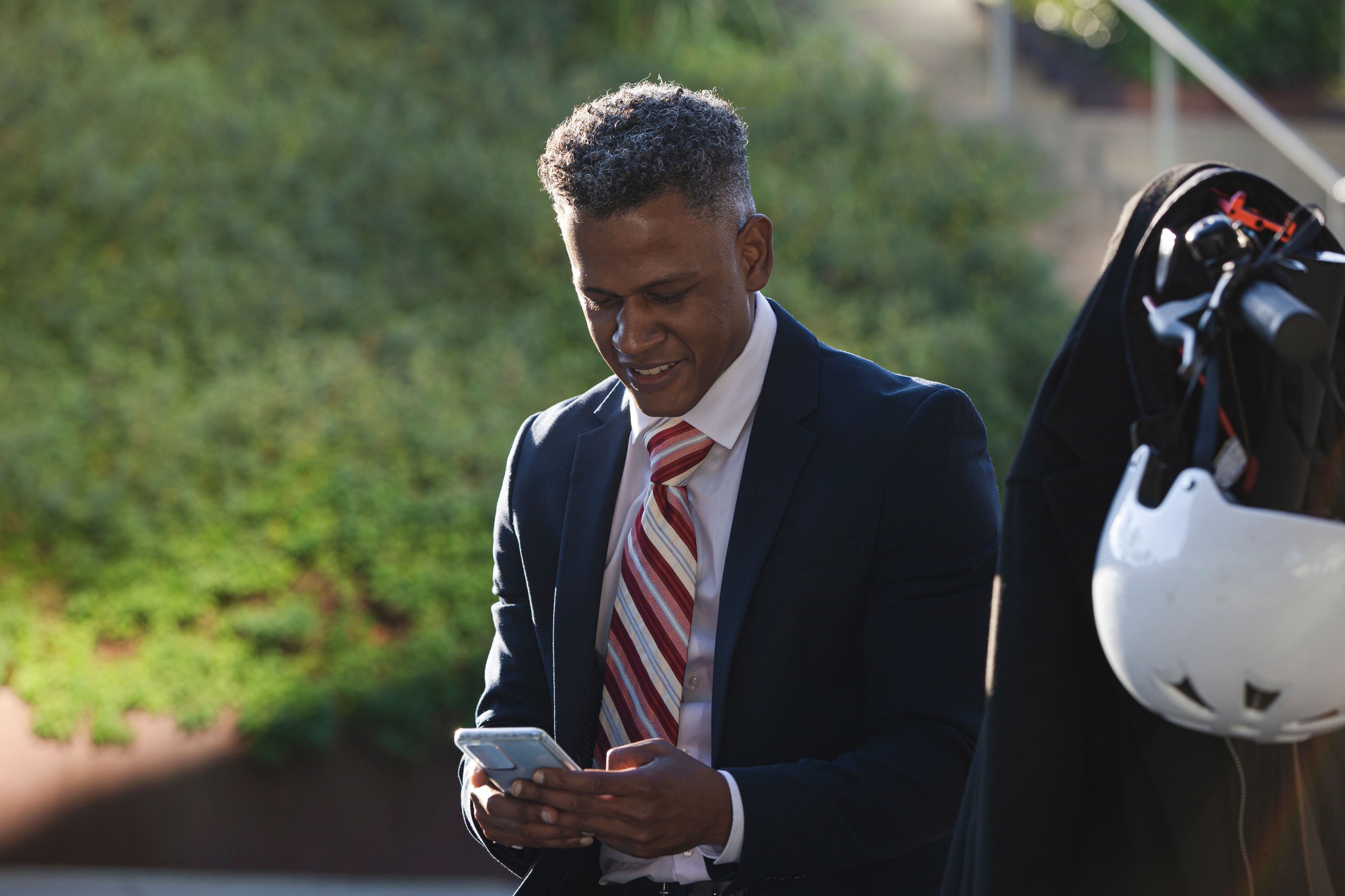 Young businessman in a suit standing on the sidewalk and looking at his mobile phone